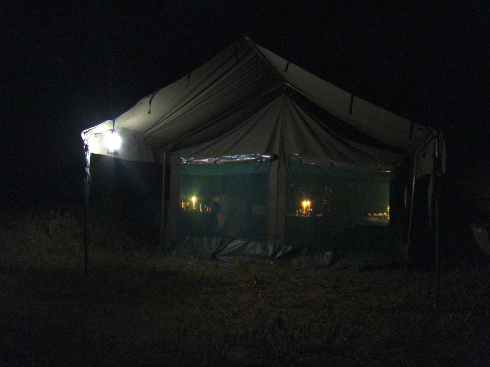 Msstlt p mobil camp efter skymningen. Camppersonalen frbereder middagen. (Sdra Serengeti National Park, Tanzania)
